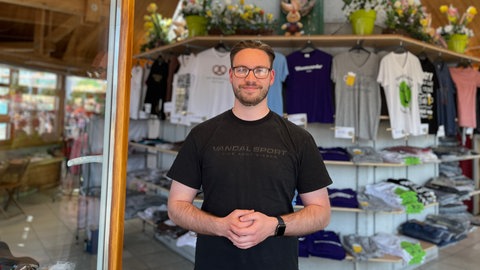 Ein Mann steht im Info- und Souvenirstand auf dem Frühlingsfest in Stuttgart.