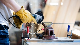 Ein Handwerker flext an einem Metallstück. Es werden weiter Auszubildende im Handwerk in der Region Stuttgart gesucht. (Symbolbild)