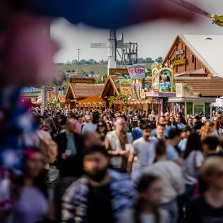 Besucher strömen bei schönem Wetter über das 85. Stuttgarter Frühlingsfest.