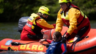 Mitglieder der Deutsche Lebens-Rettungs-Gesellschaft (DLRG) ziehen bei einer Übung im Neckar in Stuttgart einen Mann aus dem Wasser.