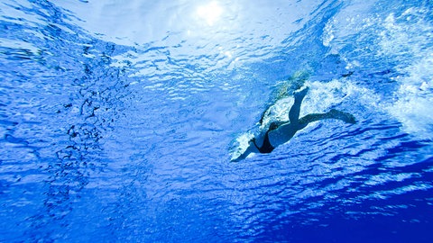 Eine Frau schwimmt in einem Freibad.