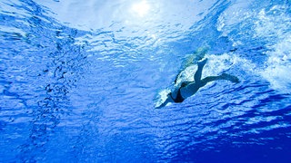 Eine Frau schwimmt in einem Freibad.