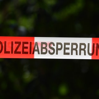 Ein Absperrband der Polizei sichert einen Tatort. In einem Wald bei Sindelfingen haben Arbeiter eine Frauenleiche entdeckt.