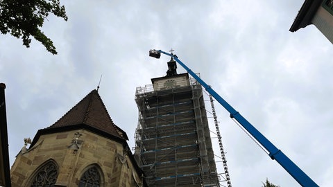 Eine Hebebühne wird an einem Kirchturm hochgefahren.