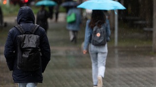 Personen gehen im Regen durch die Stadt