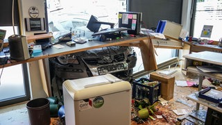 Ein Auto, dass durch eine Glasfassade in ein Büro gekracht ist. 