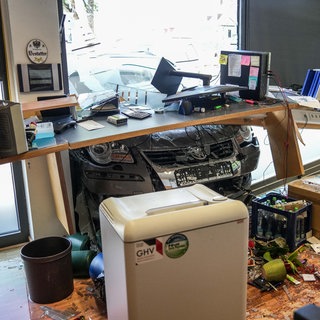 Ein Auto, dass durch eine Glasfassade in ein Büro gekracht ist. 
