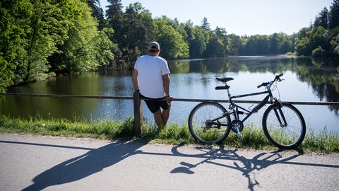 Ein Mann macht am Pfaffensee auf einer Fahrradtour eine Pause.