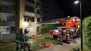 Die Feuerwehr untersucht über eine Drehleiter die Brand-Wohnung in einem Mehrfamilienhaus in Stuttgart-Hallschlag. Rund 40 Menschen mussten in der Nacht in Sicherheit gebracht werden. Die Wohnung ist nicht mehr bewohnbar.