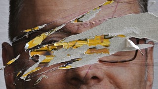 Vandalismus und Sachbeschädigung: Auf einem Plakat sind die Augen der Person ausgekratzt. (Symbolbild)