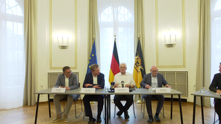 Philipp Nagl, Vorstandsvorsitzender der DB InfraGO AG, Richard Lutz, Vorstandsvorsitzender der Deutschen Bahn AG, Verkehrsminister Winfried Hermann (Grüne) und Ministerpräsident Winfried Kretschmann (Grüne) sitzen an einem Tisch nach em Bahngipfel.