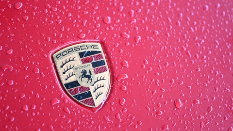 Regentropfen auf einem roten Auto mit Porsche-Logo. Der Autobauer verkauft im ersten Halbjahr 2025 weniger Autos. (Symbolbild)