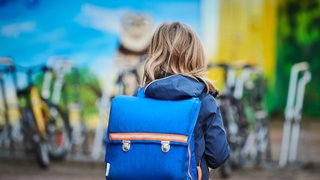 Ein Mädchen mit Schulranzen von hinten gezeigt auf dem Weg zur Schule: Zehnjährige wurde in Wernau von einem Unbekannten bedrängt. Er wollte sie in sein Auto ziehen. (Symbolbild)