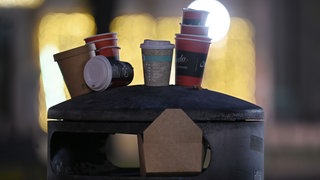 Leere Pappbecher stehen auf einem Mülleimer (Symbolbild). In Göppingen wird derzeit über eine mögliche Verpackungssteuer diskutiert.