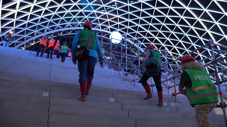 Im Inneren des enthüllten Eingangsportals von Stuttgart21 stehen Menschen auf einer Treppe