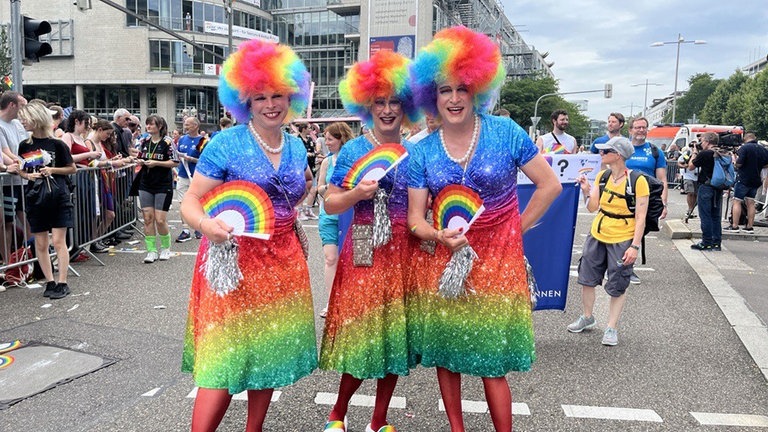 Ein Trio in Regenbogenbunt posiert bei der CSD-Parade 2024 durch Stuttgart (Archivbild).