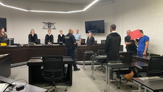 Der Angeklagte im Mordprozess verbirgt sein Gesicht hinter einer roten Mappe (Archivbild).