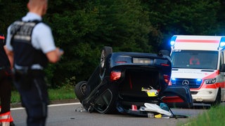 Ein Auto liegt auf einer Straße in Göppingen auf dem Dach. Dahinter ein Rettungswagen. Die Polizei ermittelt, ob es sich um ein illegales Autorennen gehandelt hat. 