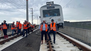 Der baden-württembergische Verkehrsminister Winfried Hermann (Grüne) steht vor einem Zug auf Gleisen. Anfang September fuhr er mit einem Testzug über die neue Strecke von Wendlingen auf die Fildern. 