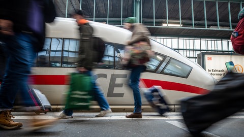 Fahrgäste laufen an einem Bahnsteig des Stuttgarter Hauptbahnhofs an einem ICE vorbei. (Archivbild)