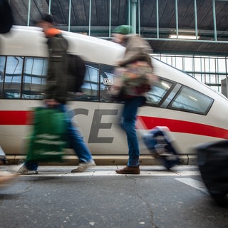 Fahrgäste laufen an einem Bahnsteig des Stuttgarter Hauptbahnhofs an einem ICE vorbei. (Archivbild)