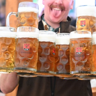 Ein Kellner trägt bei der Eröffnung des Cannstatter Wasen mehrere Bierkrüge. 