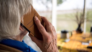 Ein Senior hält ein Telefon in der Hand. Auch in der Region Stuttgart werden seit Jahren ältere Menschen von Betrügern angerufen. (Symbolbild) 
