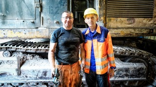 Zwei Männer stehen auf einer Baustelle.