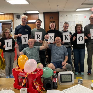 Eine Gruppe hält die Einzelbuchstaben des Begriffs Weltrekord vor dem Körper und umrahmt damit die beiden Kegel-Weltmeister in Stuttgart.