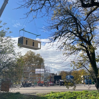 Holzmodul schwebt an Kran auf Schwimmbadbaustelle