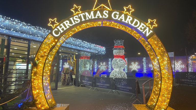 Ein Torbogen mit der Aufschrift Christmas Garden leuchtet