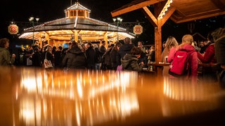 Besucher gehen über den Weihnachtsmarkt in Stuttgart.