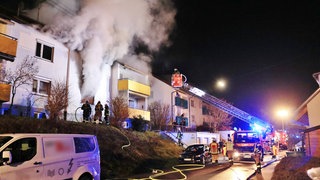 Bei einem Wohnungsbrand in Backnang stirbt eine Frau. Feuerwehrkräfte löschen den stark rauchenden Brand mithilfe eines Krans.