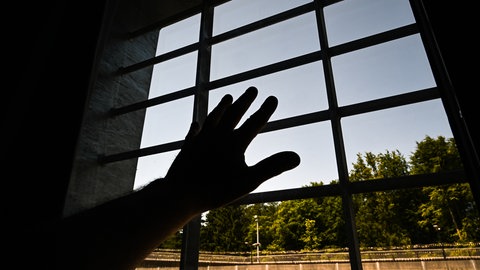 Eine Hand hinter Gittern (Symbolbild)