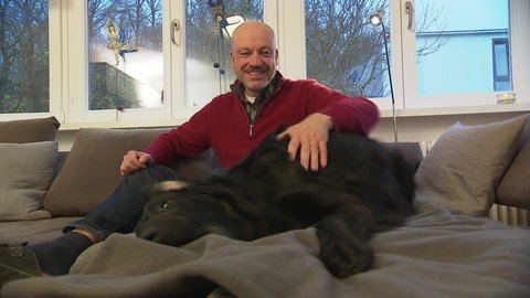 Gerd Breitfeld streichelt seinen Hund und ist froh darüber, dass er trotz seiner HIV-Diagnose inzwischen 66 Jahre alt geworden ist.