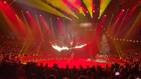 Ein Artist aus der Mongolei wirbelt einen brennenden Holzstamm durch die Manege des Weltweihnachtscircus.