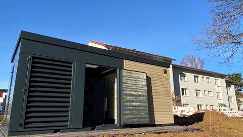 Wärmepumpen-Container steht neben Wohnhaus