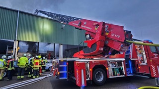 Die Feuerwehr bekämpft mit einer Drehleiter einen Brand in einer Lagerhalle in Oberstenfeld (Kreis Ludwigsburg).  