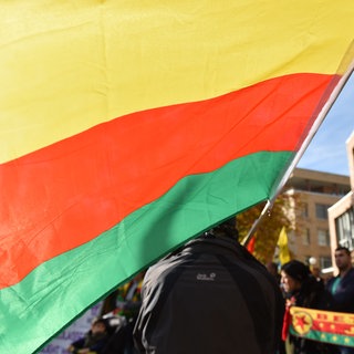 Die Flagge der nordsyrischen Autonomen Kurdenregion Rojava wird bei einer Kundgebung von Kurden in Stuttgart von einem Mann in der Hand gehalten. (Symbolbild)