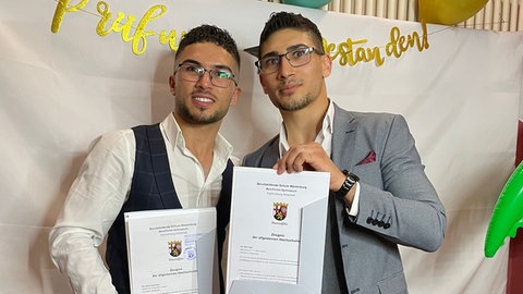 Ramzi und sein Bruder Bilal Awat Nabi halten ihr Abiturzeugnis in den Händen. Die Brüder haben 2022 in Rheinland-Pfalz ihren Abschluss gemacht.