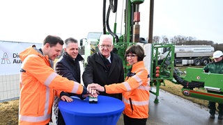 Vier Personen, darunter Winfried Kretschmann, drücken gemeinsam auf den symbolischen Startknopf für den Beginn des Ausbaus am Albaufstieg.