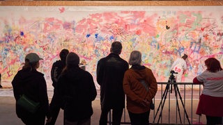 Menschen stehen vor einer großen Kunstintalation in den Waagenhallen während der Langen Nacht der Museen in Stuttgart 2025.