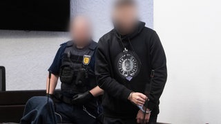 Der Angeklagte (r) im Prozess wegen Mordes an einer Frau auf dem Heimweg von der Arbeit wird in einen Saal des Landgerichts geführt. 