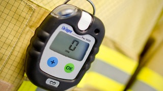 Ein Kohlenmonoxid-Messgerät (CO-Messgerät) hängt an einer Feuerwehrjacke.