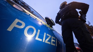 Eine Polizistin steht im Rahmen eines Fototermins neben einem Polizeifahrzeug.