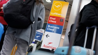 Fluggäste stehen an Lufthansa-Schaltern am Flughafen Stuttgart zum Check-In an.