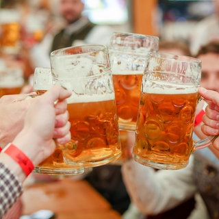 Menschen stoßen mit gefüllten Bierkrügen an. Die Bierpreise sollen beim disjährigen Stuttgarter Frühlingsfest nicht steigen.