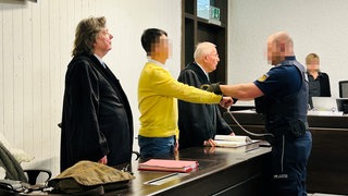 Prozess unter anderem wegen Einschleusens von Ausländern und illegaler Beschäftigung: Hier der Angeklagte mit zwei seiner Verteidiger zu Prozessbeginn. (Archivbild)