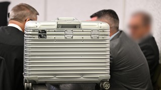 Ein Koffer diente beim Prozessauftakt als Sichtschutz: Investor Michael W. (79, rechts) und sein Sohn Mark W. (46, Mitte) sitzen neben einem ihrer Verteidiger vor dem Landgericht Stuttgart: Die beiden hatten den Gewa-Tower in Fellbach gebaut, waren aber 2016 in die Insolvenz geschlittert.