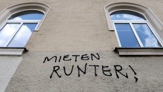 Der Schriftzug "Mieten runter!" ist an die Fassade eines Hauses geschrieben.